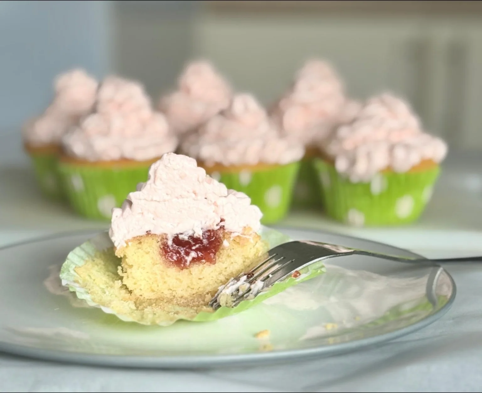 Cupcake cut open to show its jam filling and pink frosting